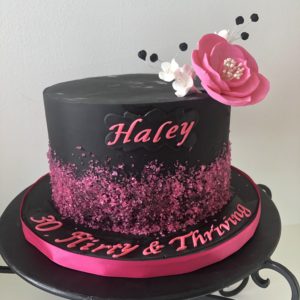 Black fondant cake with pink sprinkles and pink flower