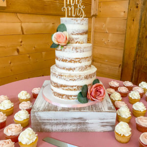 Three tiered naked wedding cake with blush accents