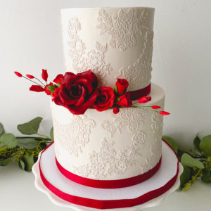 White cake with white edible lace and gumpaste red roses