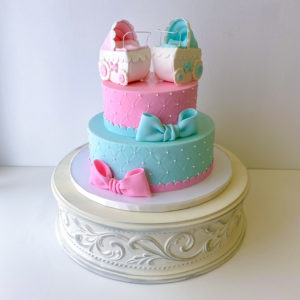 Two tiered pink and blue baby shower cake with 2 baby carriages on top