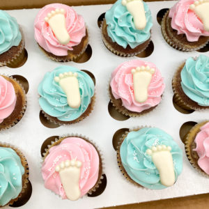 Pink and blue cupcakes with white baby feet on top