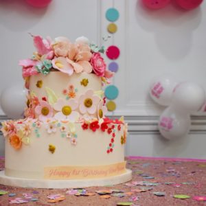 Two tiered fondant birthday cake with multiple colored sugar flowers