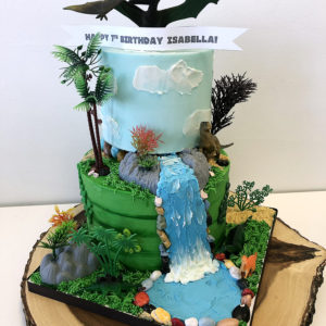 Buttercream scene with plastic dinosaurs, trees and rocks