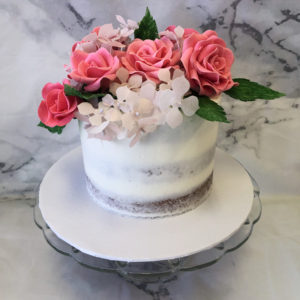 Sugar roses and wafer paper flowers on top a semi-naked cake