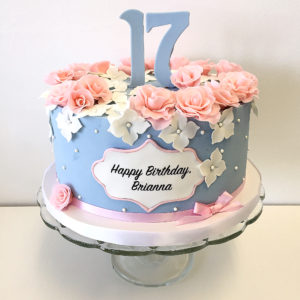 Round fondant cake with small pink fondant roses, white flowers and edible pearls.