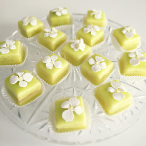Green petit fours with white flowers on top