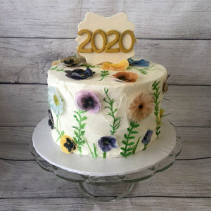 A special graduation cake with wafer paper pansies and daisies around the sides and a simple 2020 on top