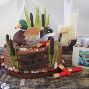 A solid chocolate duck hand painted with cocoa butter with edible shotgun shells and cat tails