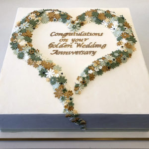 Square fondant cake with small fondant flowers in the shape of a heart