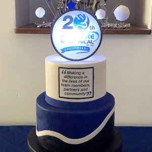 A cake to celebrate the anniversary of a electric company with a back lit logo on top