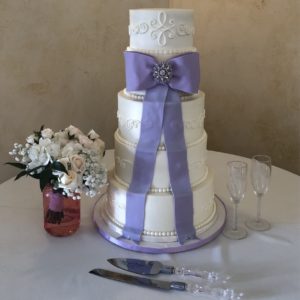 Buttercream cake with simple piping and a large lavender bow.