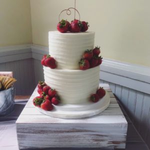 Two tiered buttercream cake with fresh strawberries