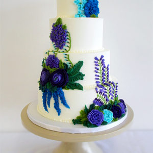 Multi tiered buttercream cake with purple and blue buttercream flowers.