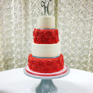 White buttercream tiers alternated with coral piped rosettes.