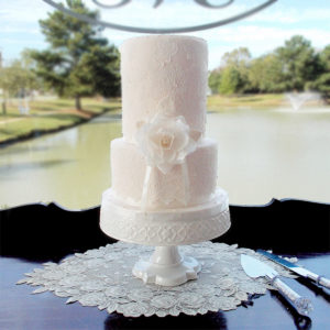 Fondant blush cake with white lace and a wafer paper flower.