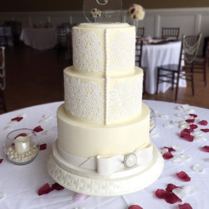 Ivory fondant cake accented with white edible lace and a fondant bow and broach.