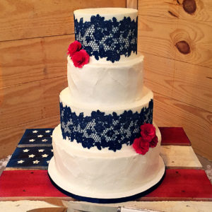 Rustic buttercream alternated with fondant tiers covered in navy edible lace and accented with wooded red roses.