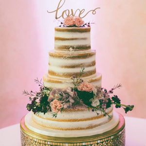Four tiered naked wedding cake with flowers provided by the bride's florist.