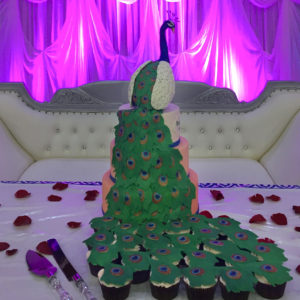 Tiered fondant cake with hand molded chocolate peacock and individual fondant feathers that feather onto cupcakes.