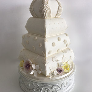 Fondant pillow cake accented with pearls, lace,  medallions and painted sugar flowers.