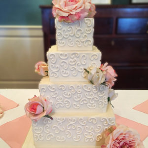 Four tier buttercream cake with piped details and accent with silk flowers.