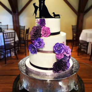 White buttercream cake with purple painted sugar flowers.