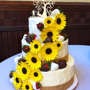 Rustic buttercream cake with sugar sunflowers and chocolate covered strawberries.