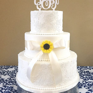 Three tiered fondant cake accented with edible lace and a gumpaste sunflower.