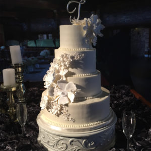 A four tiered buttercream cake with all white sugar flowers.